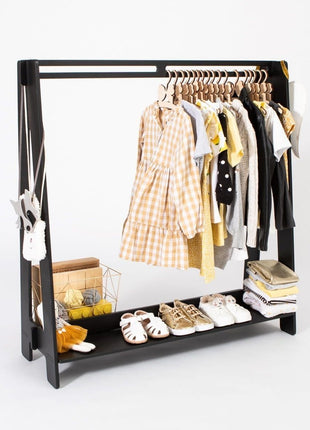Montessori Peuterkledingrek in zwart met opgehangen kinderkleding in geel, wit en grijs.