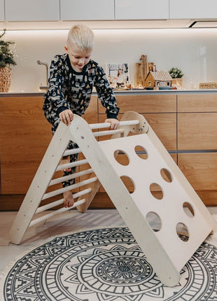Kind klimt op Montessori Waldorf klimrek in moderne keuken – actief spel binnen vertrouwde omgeving.