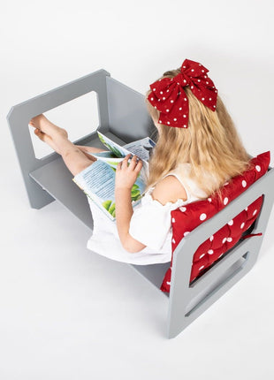 Meisje leest boek zittend op stoel van grijze Multifunctionele Montessori Speeltafel.