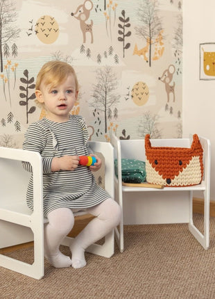 Peuter speelt zittend op stoel van witte Multifunctionele Montessori Speeltafel met Twee Stoelen.