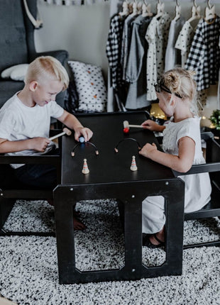 Twee kinderen spelen spel aan zwarte Multifunctionele Montessori Speeltafel met Twee Stoelen.