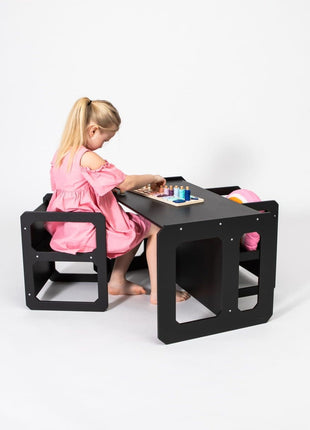 Meisje speelt met houten spel aan zwarte Multifunctionele Montessori Speeltafel met Twee Stoelen.