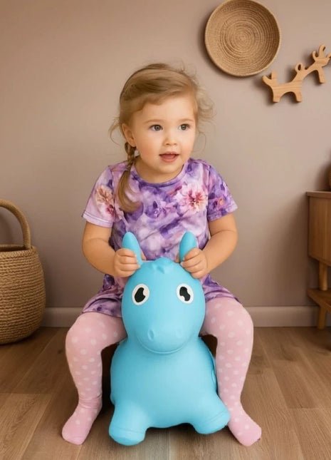 Kind zit op My First Jumpy blauw springpaard in kinderkamer.