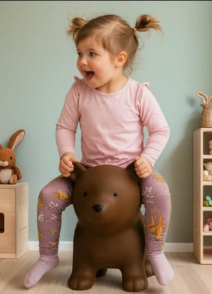 Kind zit op My First Jumpy bruin springbeer bij speelgoedkast en knuffelkonijn.