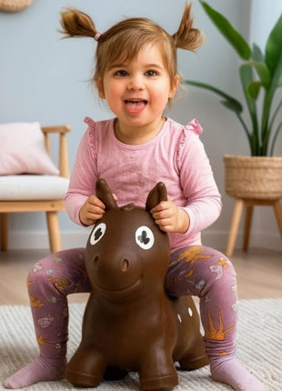 Kind zit op My First Jumpy bruin springpaard in kinderkamer in japandi sfeer.