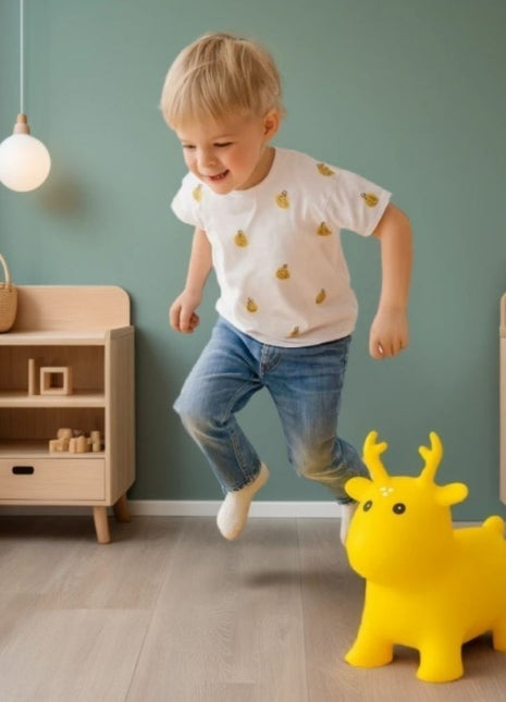 My First Jumpy geel springrendier met een springend kind ernaast in speelkamer.