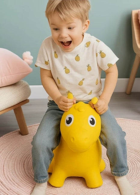 Kind zit op My First Jumpy geel springpaard op roze vloerkleed.