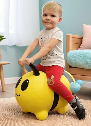 Peuter zit op gele My First Jumpy springbij met blauwe vleugels naast rotan plantenmand