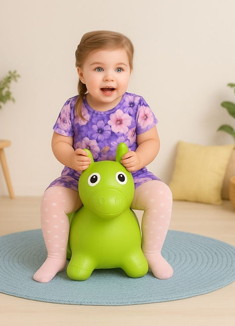 Kind zit op My First Jumpy groen springpaard op blauw vloerkleed.