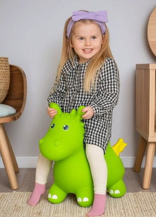 Meisje zit op groene My First Jumpy springdraak met gele staart in kinderspeelkamer