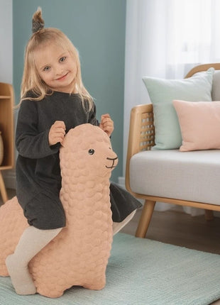 Meisje speelt op beige My First Jumpy springalpaca op blauw kleed voor bank.