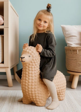 Meisje zit op beige My First Jumpy springalpaca op vloerkleed in kinderslaapkamer.