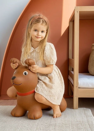 Meisje zit op bruine My First Jumpy springhond in slaapkamer met houten meubels.