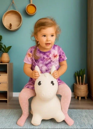 Kind zit op My First Jumpy wit springpaard in woonkamer.