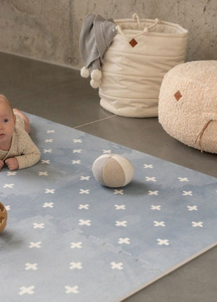 Baby op de OLYA KIDS Cross Azure speelmat met zachte ballen op betonnen vloer.