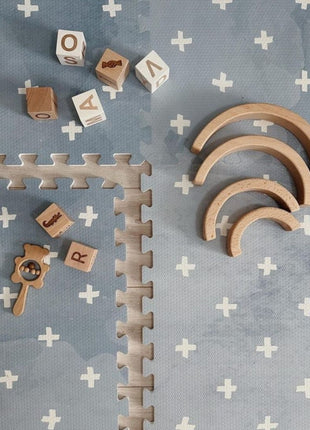 OLYA KIDS Cross Azure speelmat met houten blokken en halve regenboogbogen.