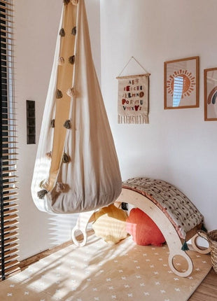OLYA KIDS Cross Sand speelmat met hangstoel en houten speelboog in speelhoek.