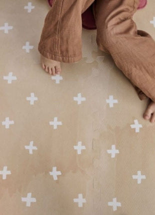 Voeten van zittend kind zichtbaar op de OLYA KIDS Cross Sand speelmat met kruisjespatroon.