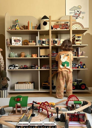 Kind staat in speelkamer op de OLYA KIDS Spots Dove speelmat met houten treinbaan.