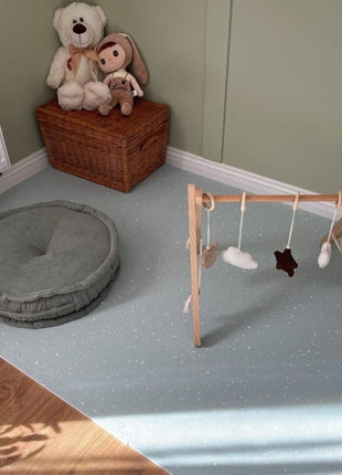 OLYA KIDS Stippen Olijf speelmat met babygym en rond kussen in hoek van een kamer.