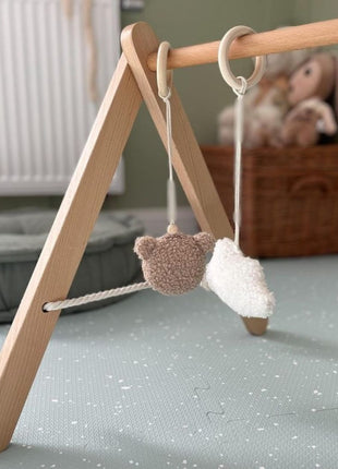 Houten babygym met pluche speeltjes op de OLYA KIDS Stippen Olijf speelmat.