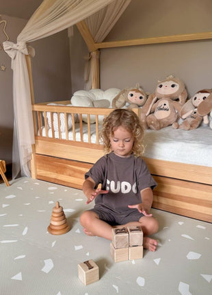 Kleuter speelt met houten blokken op de OLYA KIDS Terrazzo Dove speelmat.