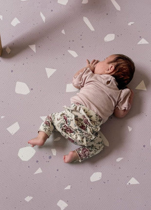 Baby ligt op de buik op de OLYA KIDS Terrazzo Lavendel speelmat met terrazzo-patroon.