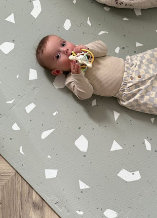 Baby speelt op de OLYA KIDS Terrazzo Sage speelmat op houten vloer.