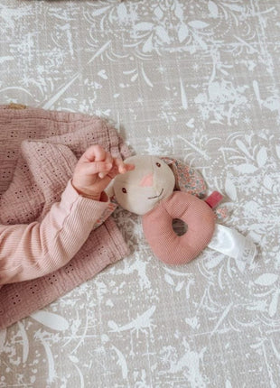 Baby op de OLYA KIDS Vintage Beige speelmat met roze knuffel-speeltje.