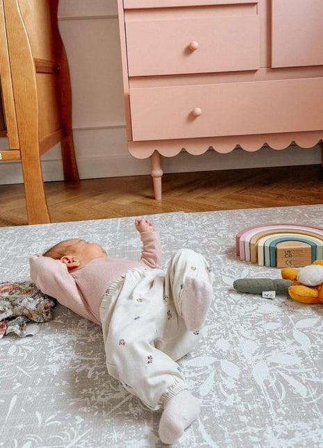 Baby op de OLYA KIDS Vintage Beige speelmat met regenboog en knuffelbloem.