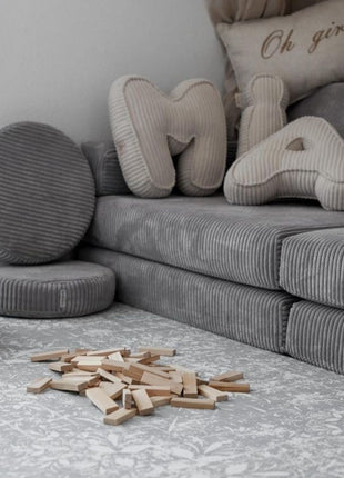 OLYA KIDS Vintage Grijs speelmat in speelhoek met grijze bank en houten blokken.