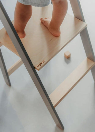Detail van kindervoeten op houten platform van Leg&Go opvouwbare keukentoren met verwijderbare rail.