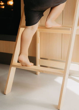 Detail van kindervoeten op houten trede van Leg&Go opvouwbare keukentoren met verwijderbare rail.