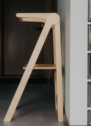 Naturel Leg&Go opvouwbare keukentoren met verwijderbare rail ingeklapt tegen muur.