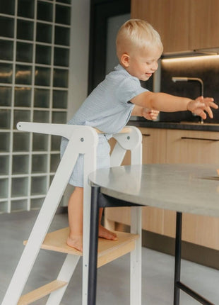 Kind staat op witte Leg&Go opvouwbare keukentoren met verwijderbare rail bij ronde tafel.