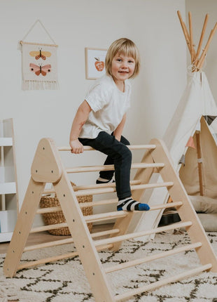 Pikler-driehoek - Naturel van leg&go met kind dat bovenop de houten spijlen zit.