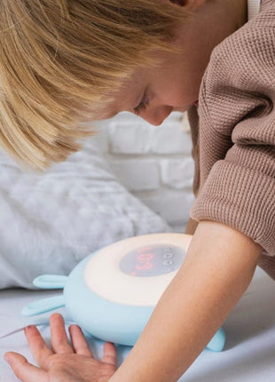 Kind bedient Rabbit and Friends Wekkerlamp met Oortjes met onderarm op bed.