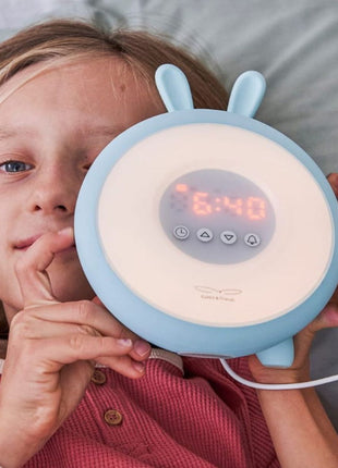 Kind houdt Rabbit and Friends Wekkerlamp met Oortjes voor zich op bed.