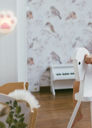 Rabbit & Friends Paw Nachtlampje verlicht aan witte kast met kind op achtergrond.