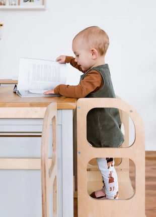 Dreumes staat in naturel STEP UP keukentoren met steunpoten en bladert in boek