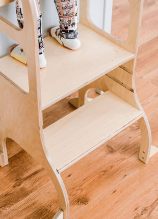 Kind staat rechtop op het platform van naturel STEP UP keukentoren met steunpoten