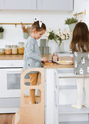 Twee meisjes staan op naturel STEP UP keukentorens met steunpoten en smeren boterhammen aan keukenblad