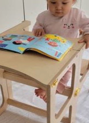 Baby leest boek aan de STEP'n'SIT® 2-in-1 keukentoren naturel in tafelstand