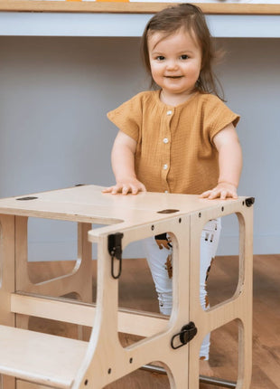 Peuter gebruikt de STEP'n'SIT® 2-in-1 keukentoren naturel in tafelstand als speeltafe