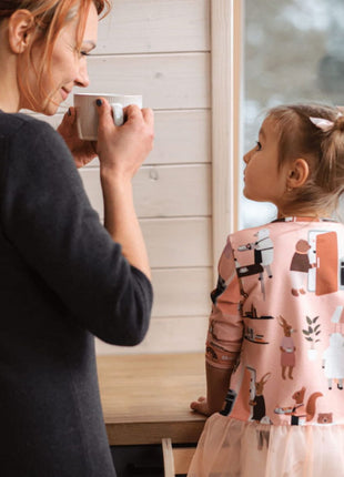 Kind staat in de STEP'n'SIT® 2-in-1 keukentoren wit met steunpoten naast ouder aan het keukenblad