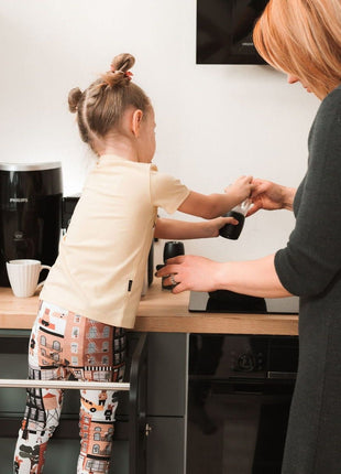 Kind en ouder bereiden samen koffie aan het aanrecht met de STEP'n'SIT® 2-in-1 keukentoren zwart