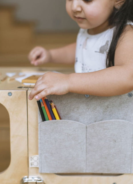 Kind pakt kleurpotloden uit pennenhouder aan STEP’n’SIT keukentoren tijdens creatief spelmoment