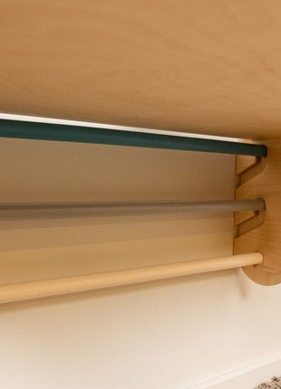 Detail van Zweedse klimwand met houten en gekleurde sporten onder gemonteerde tafel