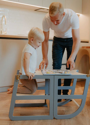 Grijze Leg&Go transformeerbare keukentoren 2-in-1 gebruikt als tafel met kind en vader.