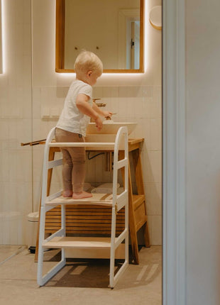 Kind staat op witte Leg&Go transformeerbare keukentoren 2-in-1 en wast handen bij wastafel in badkamer.